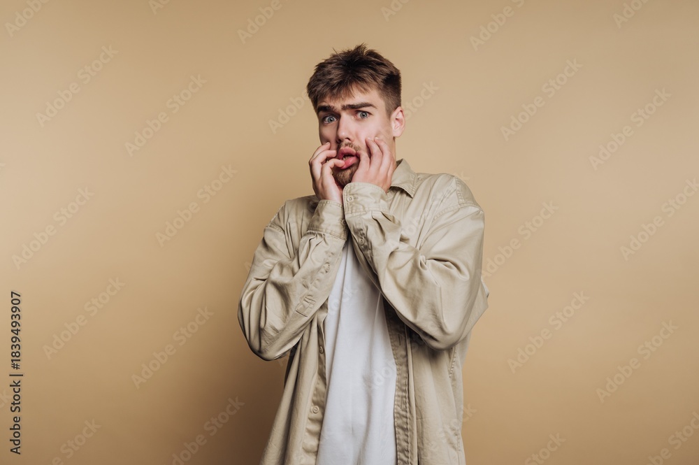 Fototapeta premium Young man with surprised expression against beige background