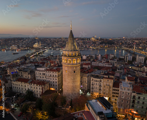 Morning view of Galata Tower and cityscape in Istanbul with lights illuminating streets and buildings at sunrise. Flying around iconic Galata Tower in historic Beyoglu district 