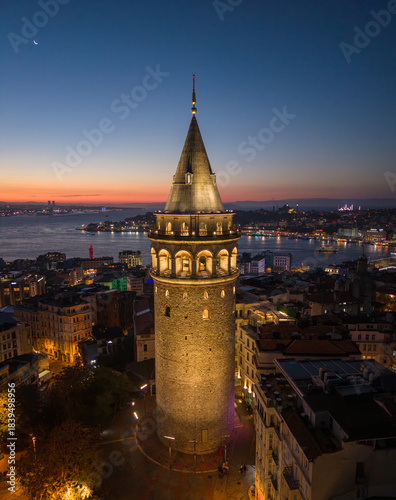 Aerial HDR shot of Galata Tower at sunrise. Galata Tower stands tall in Istanbul as daylight fades into night over the cityscape and waterways, Turkey. Vertical shot