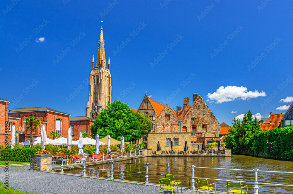 Fototapeta premium Bruges cityscape, Bakkersrei water canal of Reie river, Church of Our Lady, Old St John’s Hospital building in Brugge old town, Saint John embankment in Bruges city centre, West Flanders, Belgium