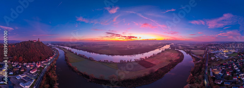 Sonnenuntergang über einem Fluss mit Hügel und Stadt