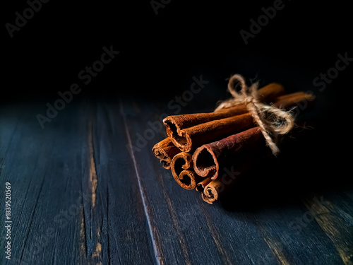 Fotografija Cinnamon sticks are arranged on a rustic wooden surface, highlighting their curled, textured appearance