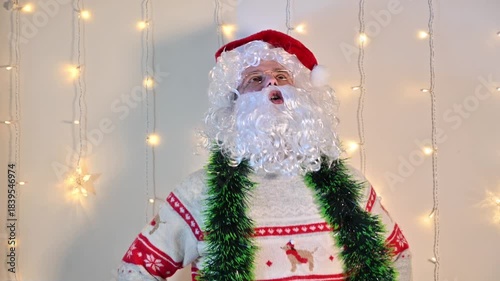 A man dressed as Santa Claus on a white background with festive lights, moving and acting like Santa in a playful and expressive holiday performance.