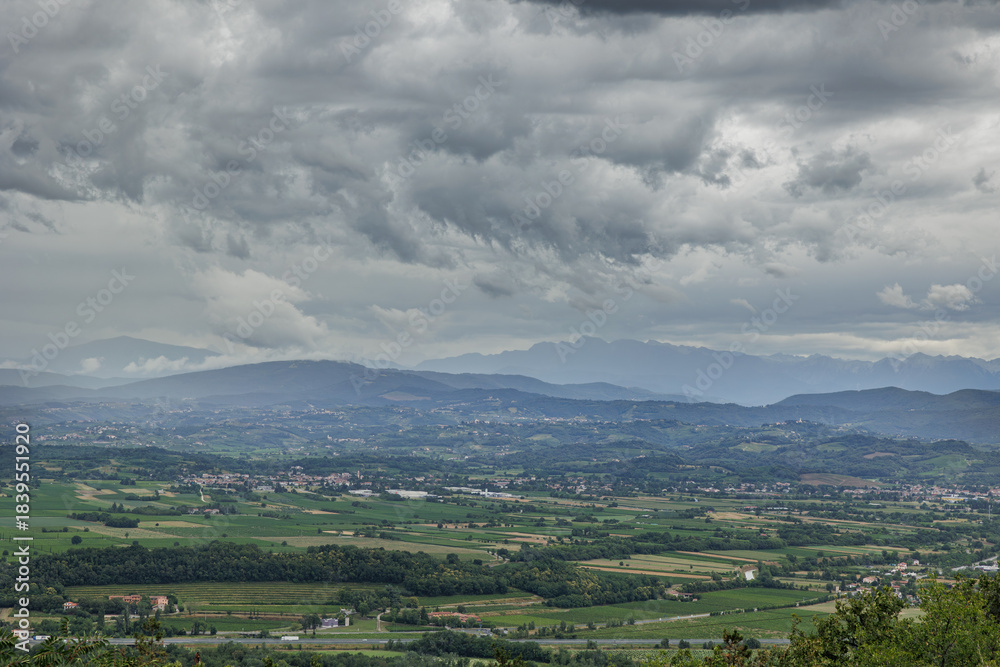 Obraz premium ambiente misto naturale ed urbano tra la pianura e le colline tra Italia e Slovenia, in estate, di pomeriggio, con cielo nuvoloso e meteo piovoso