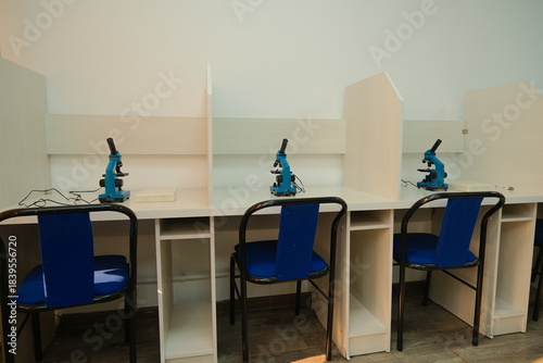Individual lab workstations with microscopes in a study room designed for scientific research.