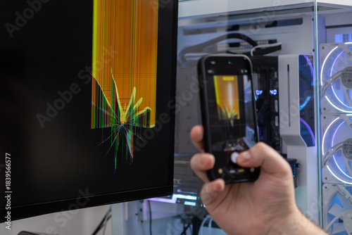 Photography Hand photographs a severely cracked computer monitor screen using a smartphone,