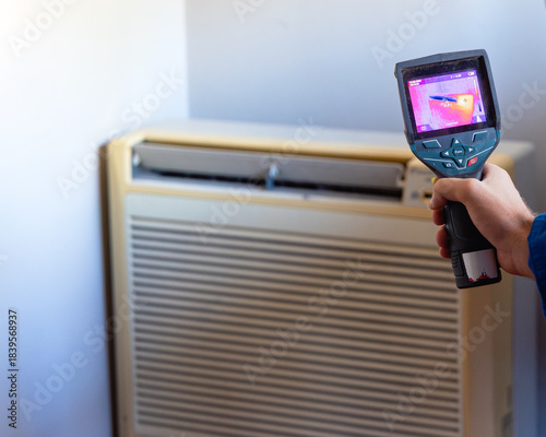 Hand using thermal camera checking air conditioner temperature