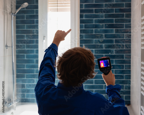 Man using thermal camera detecting leak in bathroom wall