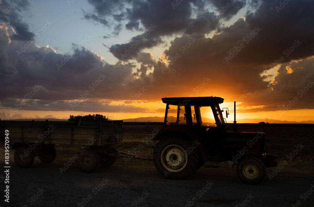 Obraz premium A tractor in a farmland at sunset.