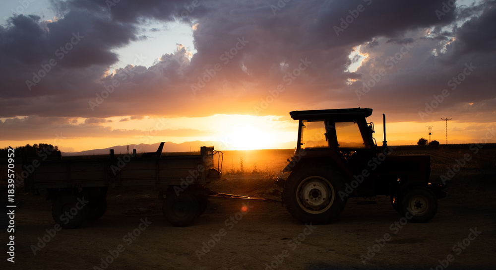 Obraz premium A tractor in a farmland at sunset