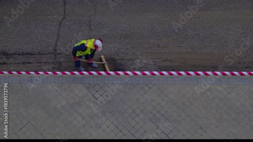 Aerial top down view of a construction worker preparing a road surface for paving with asphalt