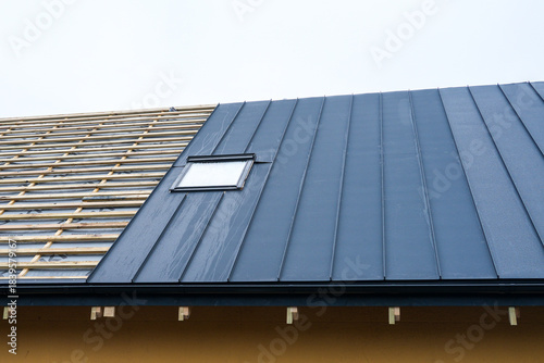 Modern metal roof installation with skylight on residential house under construction