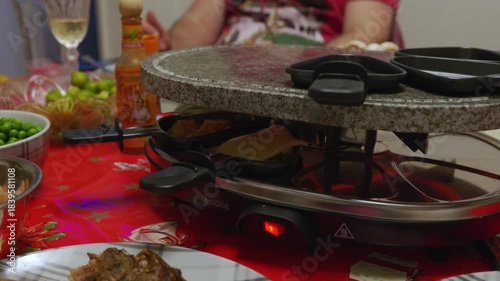 Tabletop grill with grilling plates filled with food being cooked and shared