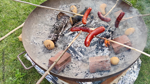 Sausages on the stick above the fire