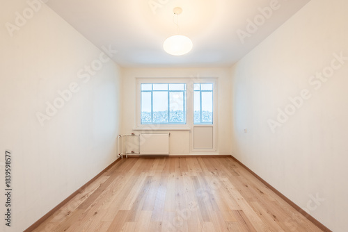 Bright Empty Room With Wooden Flooring and Large Window Overlooking Urban Scenery