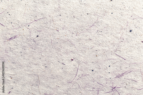 Handmade beige or light purple textured paper background with small fibers and specks, symbolizing natural craft