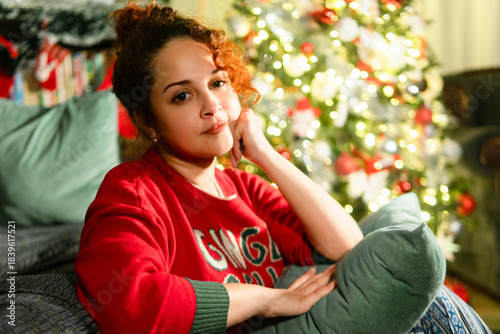 Woman relaxing at home by christmas tree