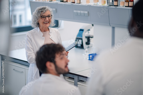 Foto Senior scientist mentoring young students in a lab