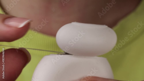 Close-up shows hand taking dental floss from white dispenser, emphasizing daily dental care. Dental hygiene with clean floss in bathroom. Oral hygiene routine with dental floss for healthy teeth.