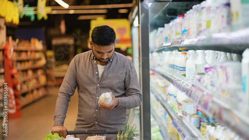 Indian man buying milk in a supermarket dairy aisle