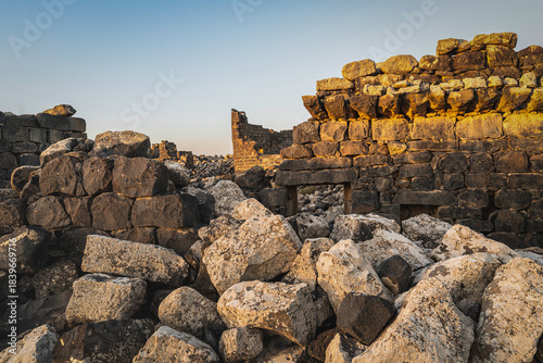 Umm Al-Jimal Sunset: Golden hour on the ancient black basalt ruins in Mafraq, Jordan. Roman tower contrasts with modern cell towers.