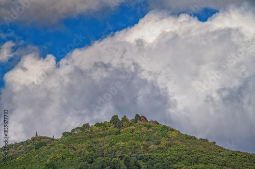 Clouds and Blue Sky Above a Green Hilltop.