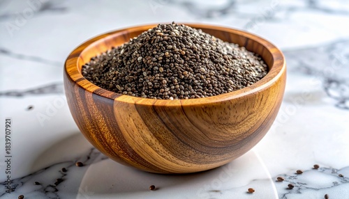 Close up photo of chia seeds in a wooden bowl on a marble surface