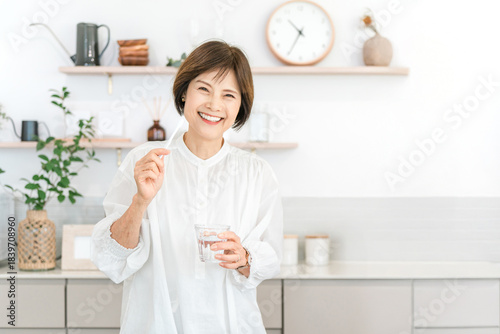 Canvas Print Senior woman brushing her teeth in the kitchen (dental care, bad breath care)