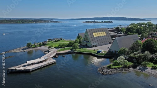 Aerial orbit of Oslo waterfront. Cinematic summer travel drone view capturing museum rooftops, green coast and blue fjord landscape.