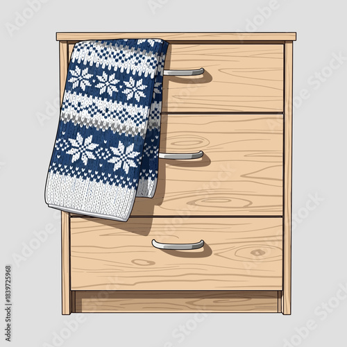 Cozy wooden chest of drawers with a patterned blue and white knitted blanket hanging from the top