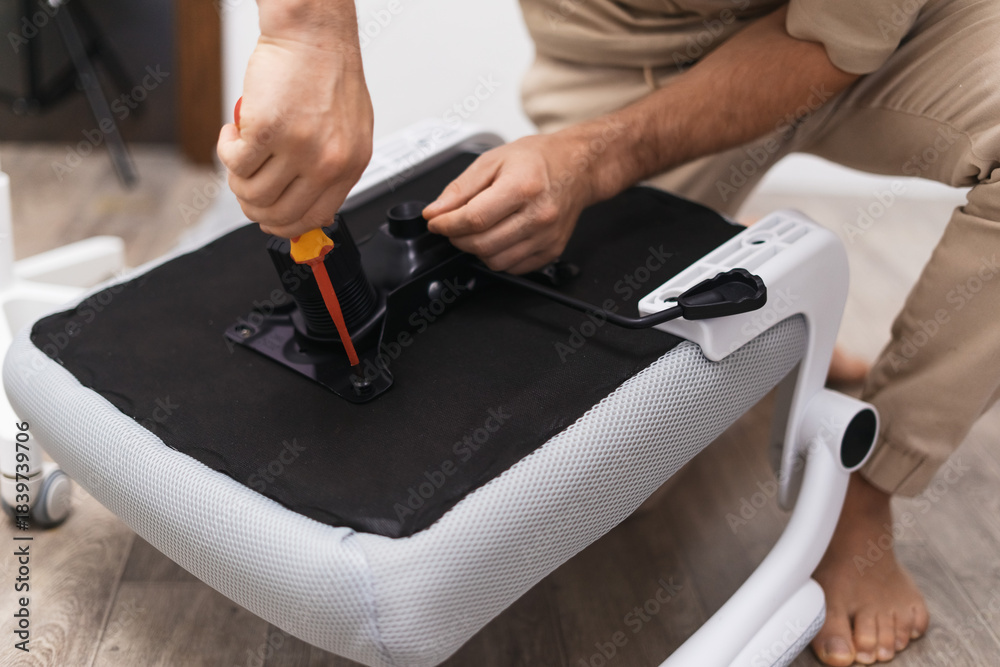 © Aboltin - Worker adjusts white office chair tightening screw with tool, focusing on repair accuracy, stable construction. Closeup shot shows manual setup supporting ergonomic comfort in modern home workspace. © Aboltin - Worker adjusts white office chair tightening screw with tool, focusing on repair accuracy, stable construction. Closeup shot shows manual setup supporting ergonomic comfort in modern home workspace.