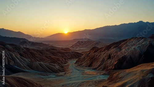 A majestic landscape of sculpted terrain and layered mountains in the warm glow of sunrise