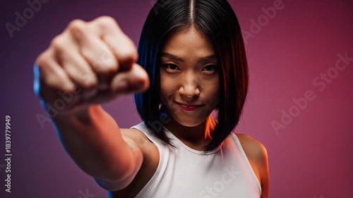 Asian woman confidently throws a punch, empowerment and determination radiate, martial arts discipline showcased in dynamic studio lighting
