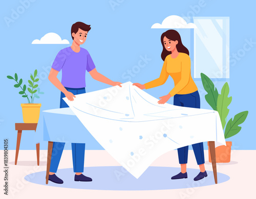 A smiling couple sets the table together, laying a fresh white tablecloth. A simple, sweet moment of teamwork and preparation at home.
