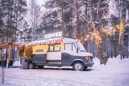 A cozy coffee shop in a winter park on Christmas Eve. A food truck in the woods in winter. High quality photo