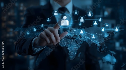 Businessman touching a glowing human icon connected to a global network map representing digital connection, human resource management, and worldwide business strategy