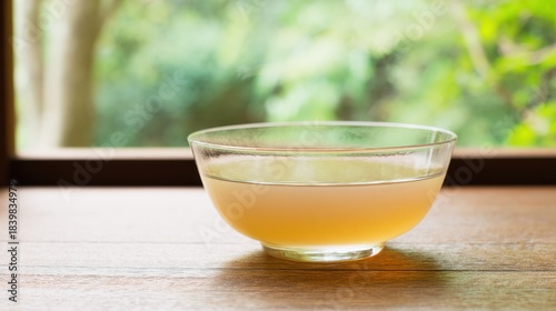 Clear glassware filled with a bowlful of delicate consomme soup, captured in bright natural lighting for branding.