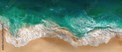 Aerial View of Turquoise Ocean Waves Gently Lapping on Sandy Beach Shoreline with Clear Water and Foam Patterns