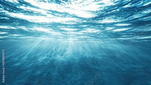 Stunning underwater view looking up towards the bright sunlit surface of the deep blue ocean water