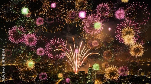 Vibrant Fireworks Display Illuminates Cityscape at Night with Golden Pink Green Bursts