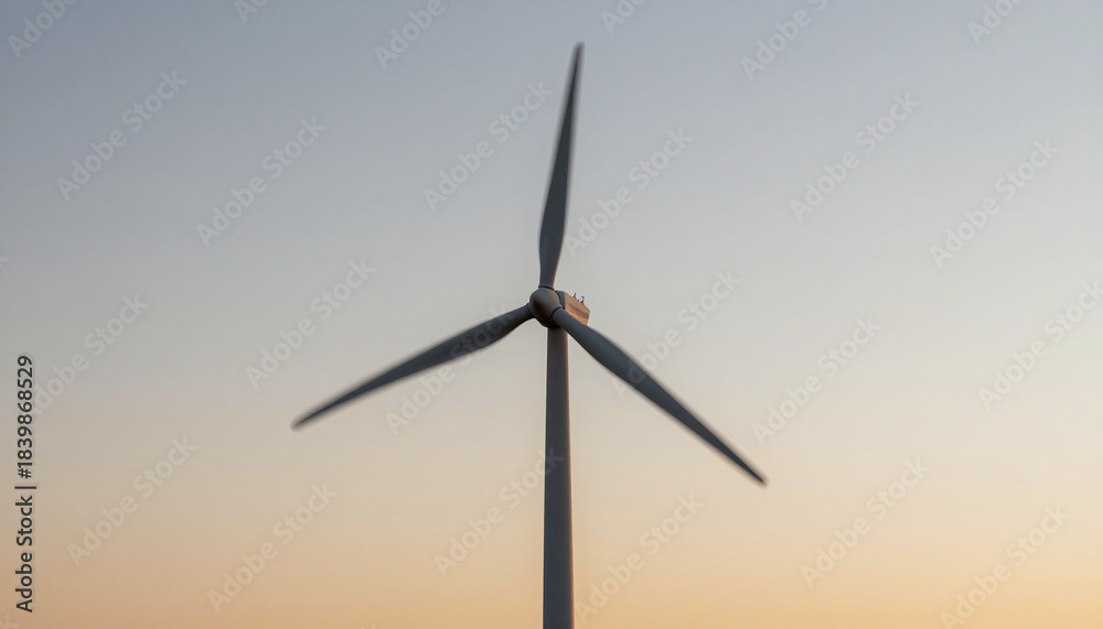 Fototapeta premium Wind turbine blades motion blur against a sunset sky, clean energy motion