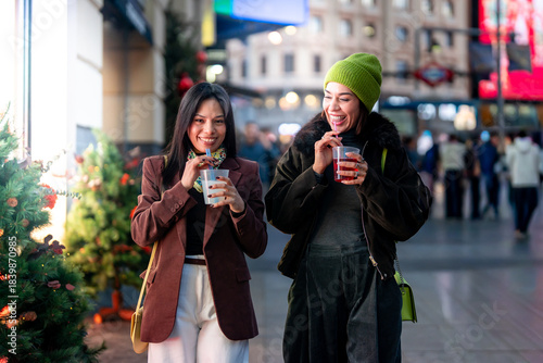 Women friends laughing enjoying drinks during christmas night