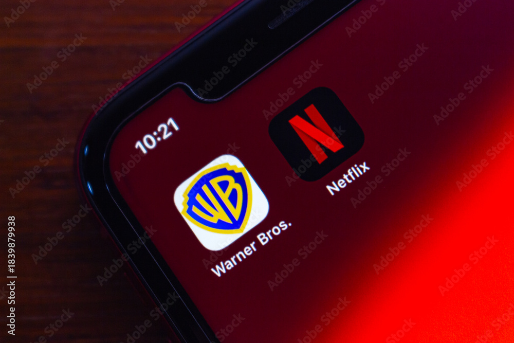 Naklejka premium Quito, ECUADOR - Dec 9 2025 : Close-up of Warner Bros and Netflix icons on iPhone, highlighting the ongoing merger news, streaming competition and shifting dynamics in the entertainment industry.