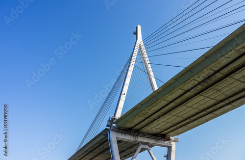 Tempozan Bridge Pylon and Cables Against Blue Sky with Copy Space. Worm's-eye view of the massive pylon and tensioned cables of the Tempozan cable-stayed bridge in Osaka, Japan.