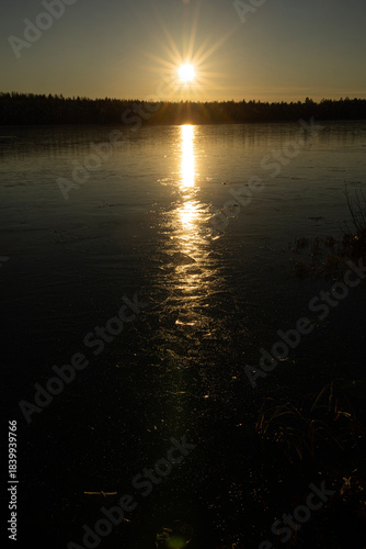 Moon on night sky over winter lake at night time. A moonlit path on the lake's ice in winter.
