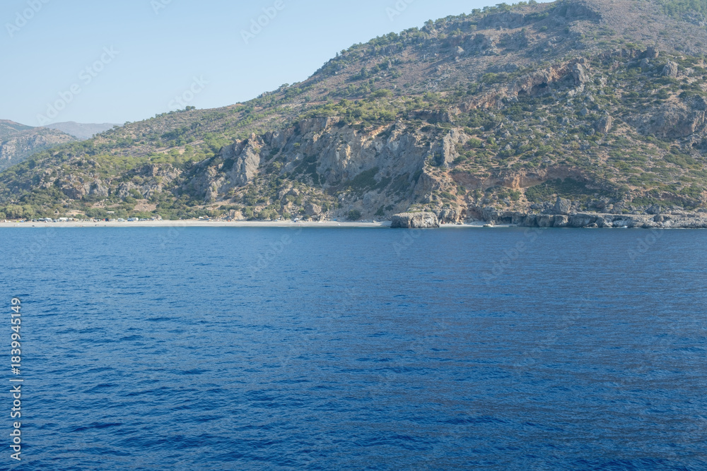 Fototapeta premium Rocky coastline and deep blue sea at Sougia beach upon the southern coast of Crete, Greece, sunny summer day, blue sky