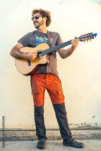 Quadro su tela Man musician playing guitar smiling outdoors