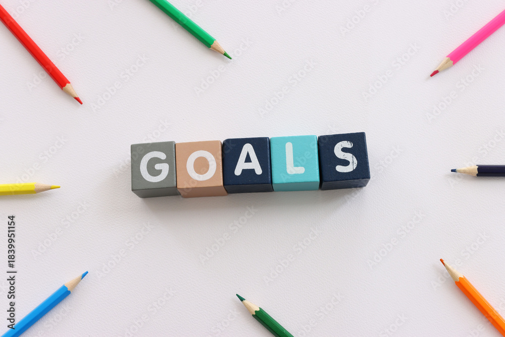 Fototapeta premium Wooden cubes with text goals on white textured background