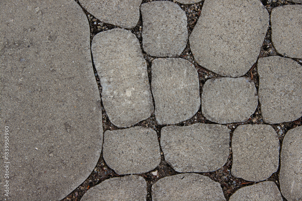 Obraz premium Textured stone pavement composed of various shapes and sizes, showcasing a natural arrangement of gray stones with earthy tones, ideal for outdoor pathways and landscaping design