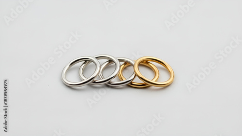 A minimalist arrangement of four abstract, organic-shaped rings, two in silver and two in gold, displayed on a plain white background.